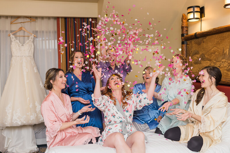 Bride and bridesmaids throwing confetti on bed at Disney