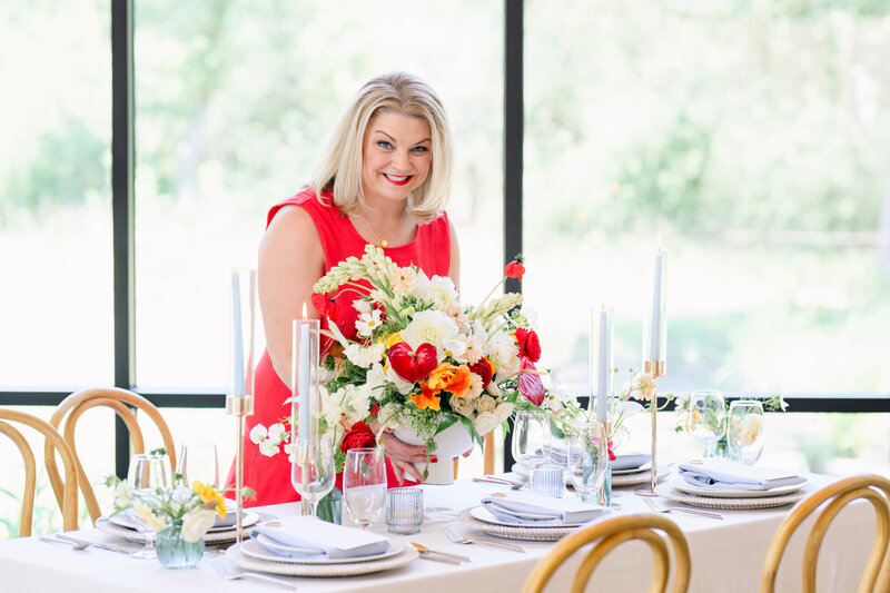 Austin wedding planner placing vibrant florals on an elegant reception table, bringing calm, confident energy to wedding day setup.