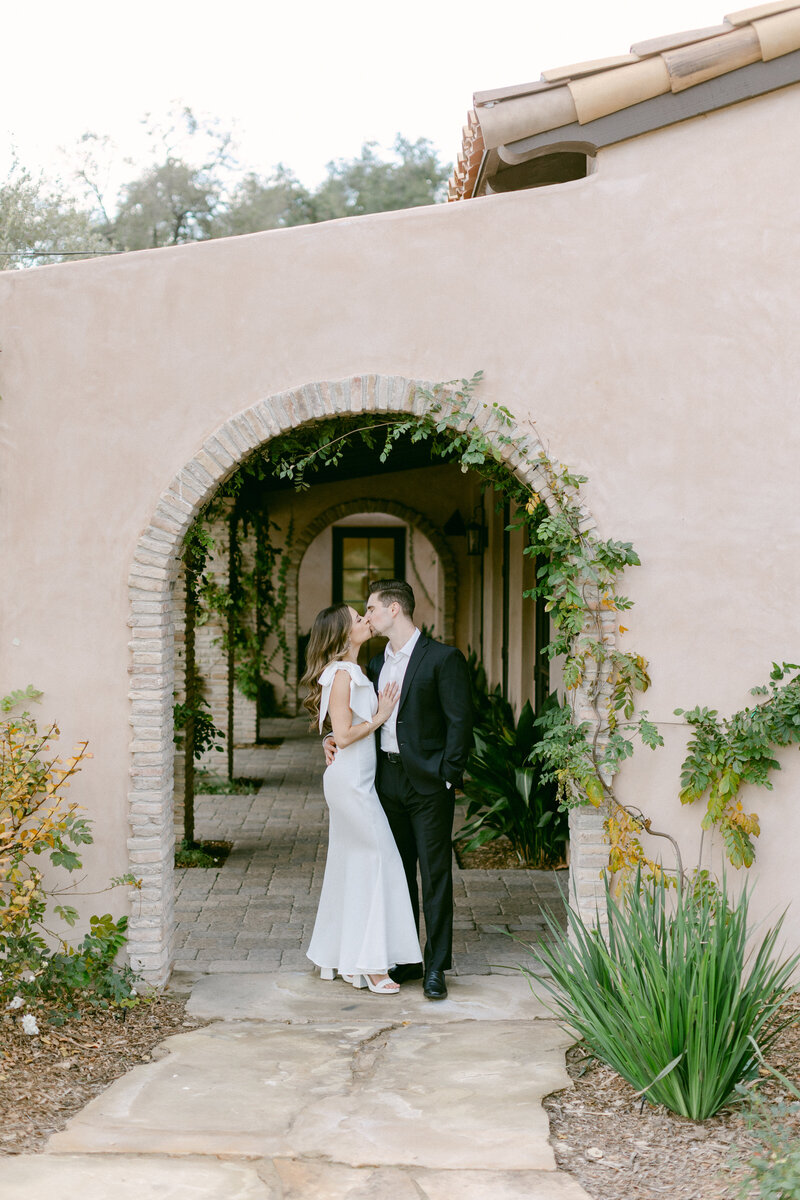 Fiance's share a kiss under a brick archway at Monserate Winery's Italian inspired villa