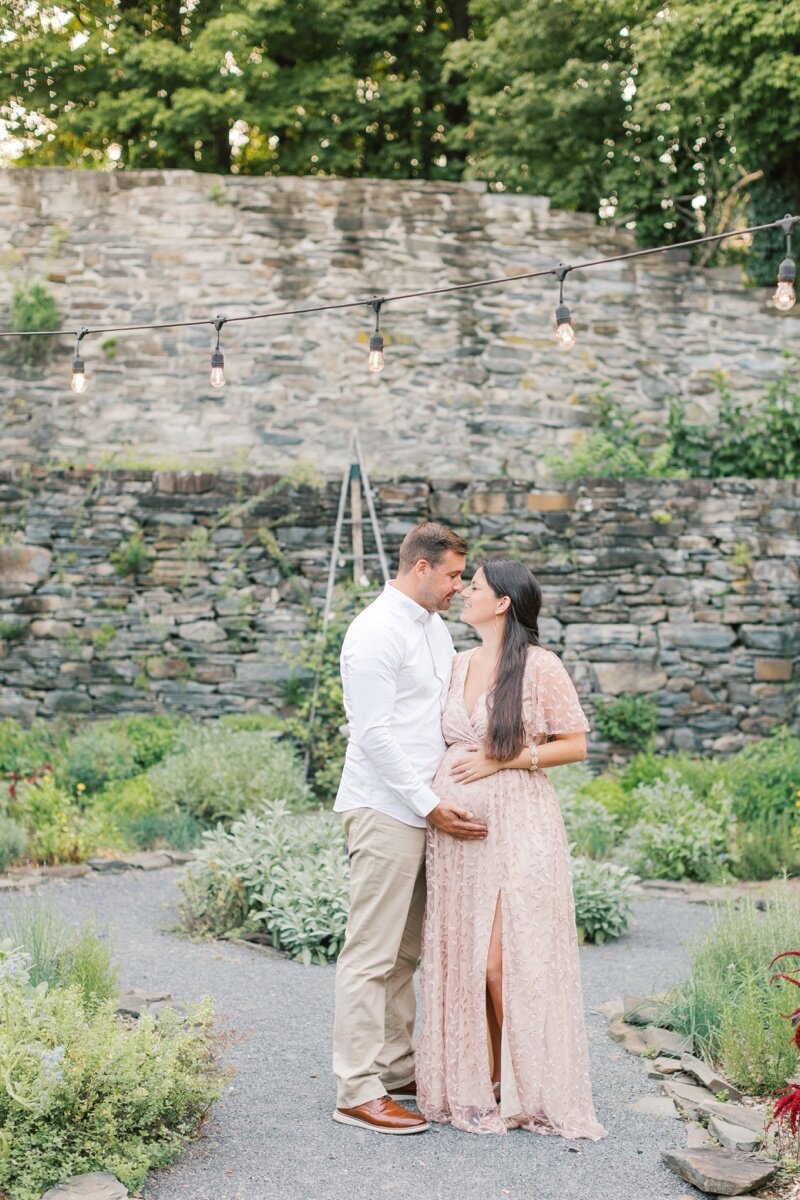 A couple stands outside in a garden during their NJ Maternity photos.