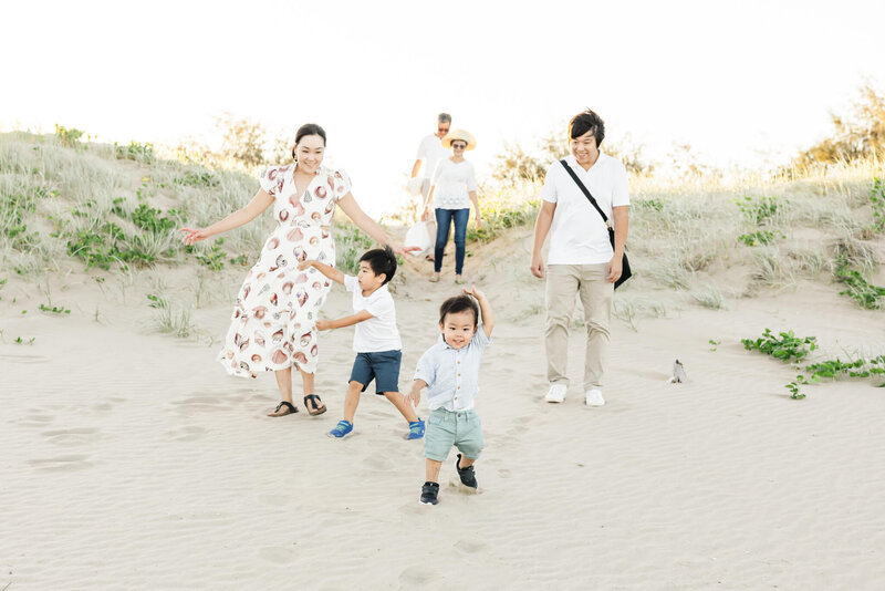 Beautiful family of four walking down to the beach including two little boys with their Dad and Mum, followed by their grandparents in the background. Photo taken at Kinka Beach, Yeppoon, Queensland.
