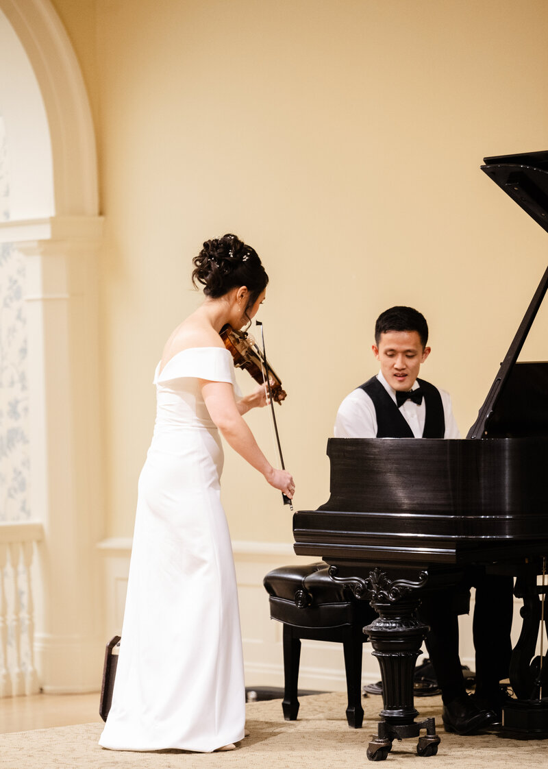 A newly married couple plays the violin and piano at their wedding at St Cecelias in Grand Rapids