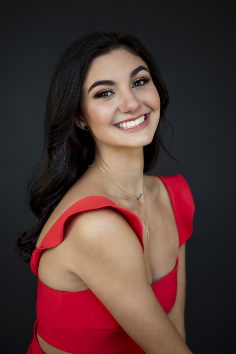 Beauty portrait of high school senior smiling in a red dress
