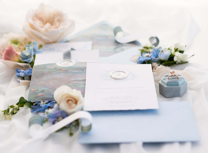 a styled flat-lay photo of a wedding invitation suite with adjacent flowers and wedding ring set taken by Ottawa wedding photographer JEMMAN Photography