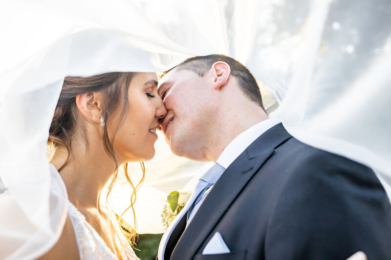 Bride and groom kiss under a flowing veil at Bohemia Overlook, Maryland Wedding