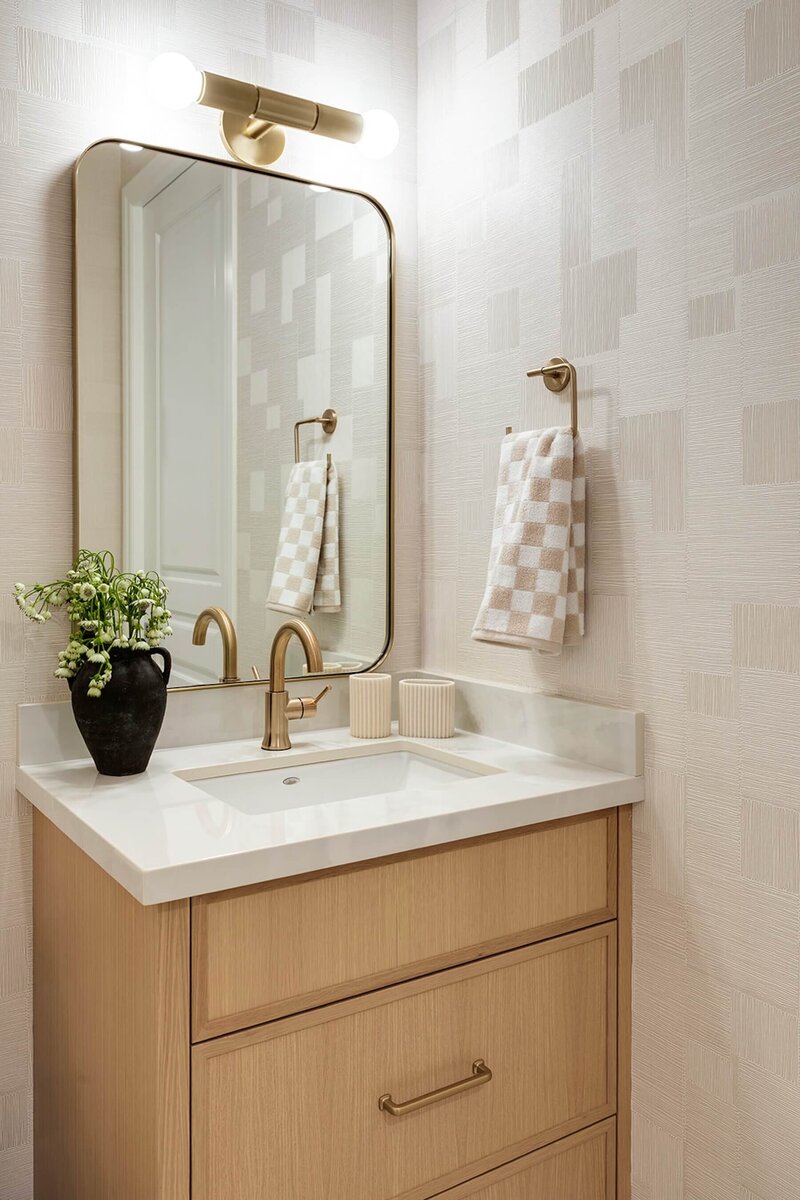 Powder room with check wall tile, white oak vanity and white quartz with gold accent lighting. 