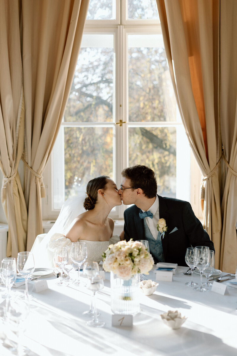 wedding coupLuxury wedding in Europe – sophisticated bride in a modern wedding gown and groom in a timeless suit.le kiss