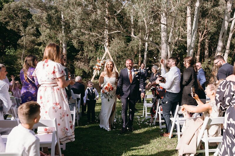 A couple having a micro wedding ceremony with their guests with a forest backdrop