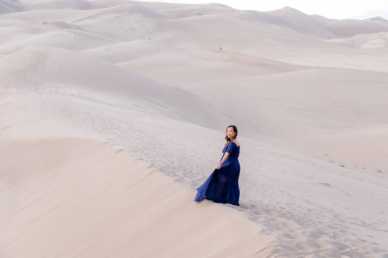 Shaochen in a navy blue dress walking in the great sand dunes