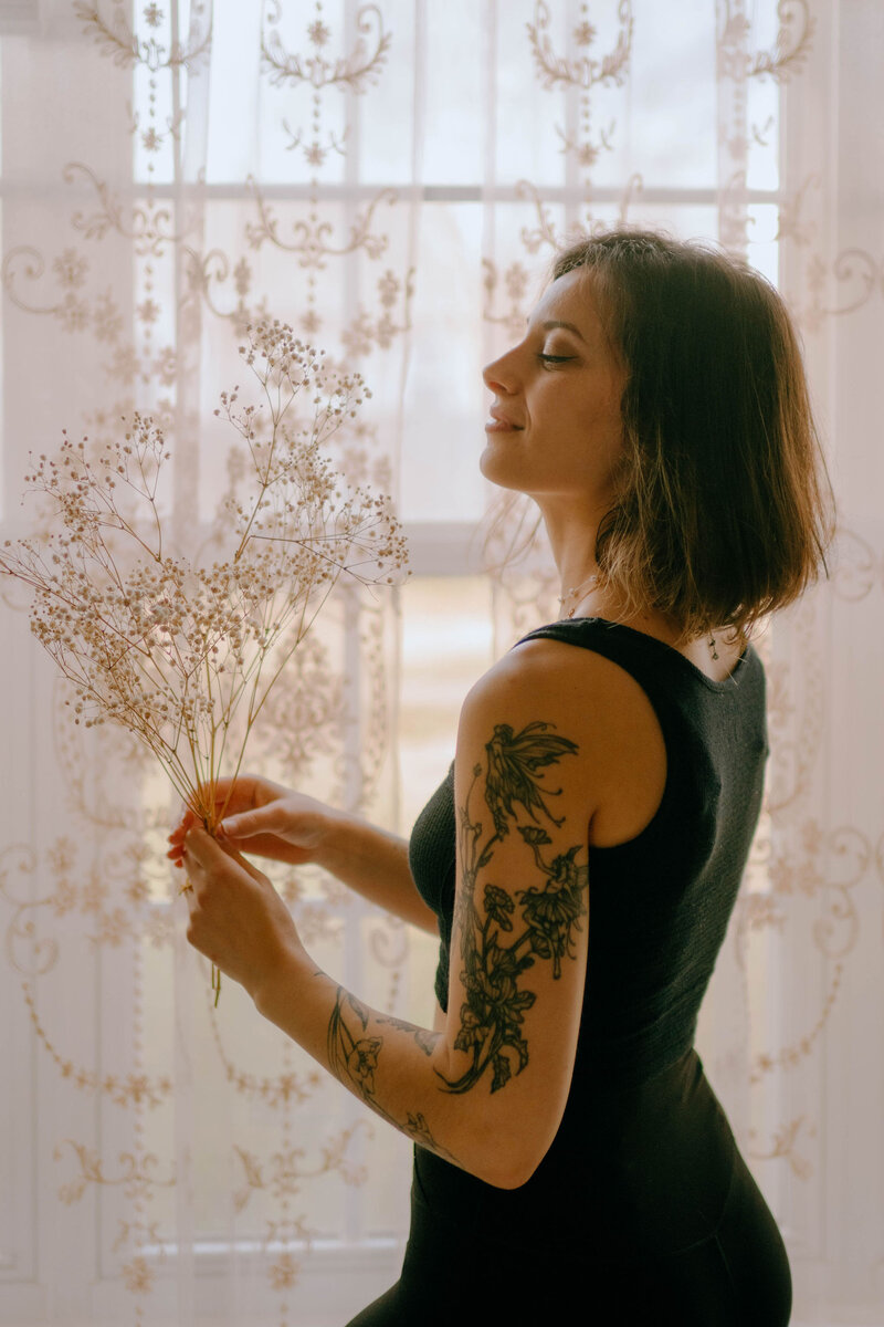 fairy tattoos in front of white curtains holding flowers