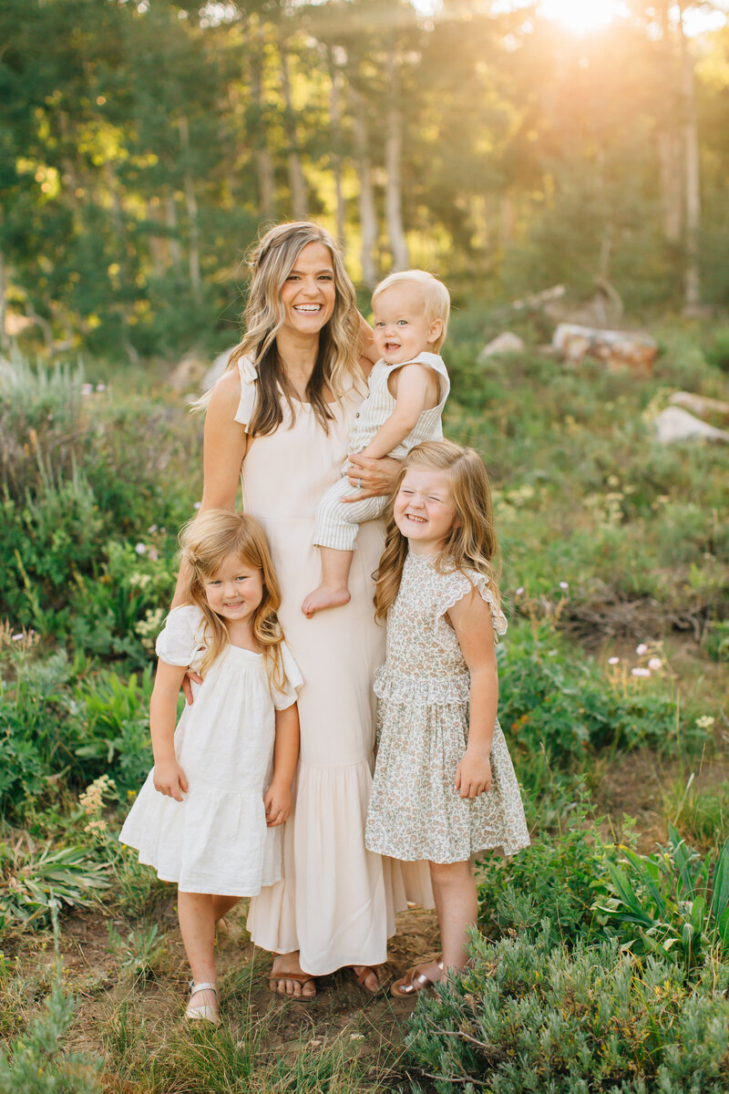 a mom standing in the forest with her children