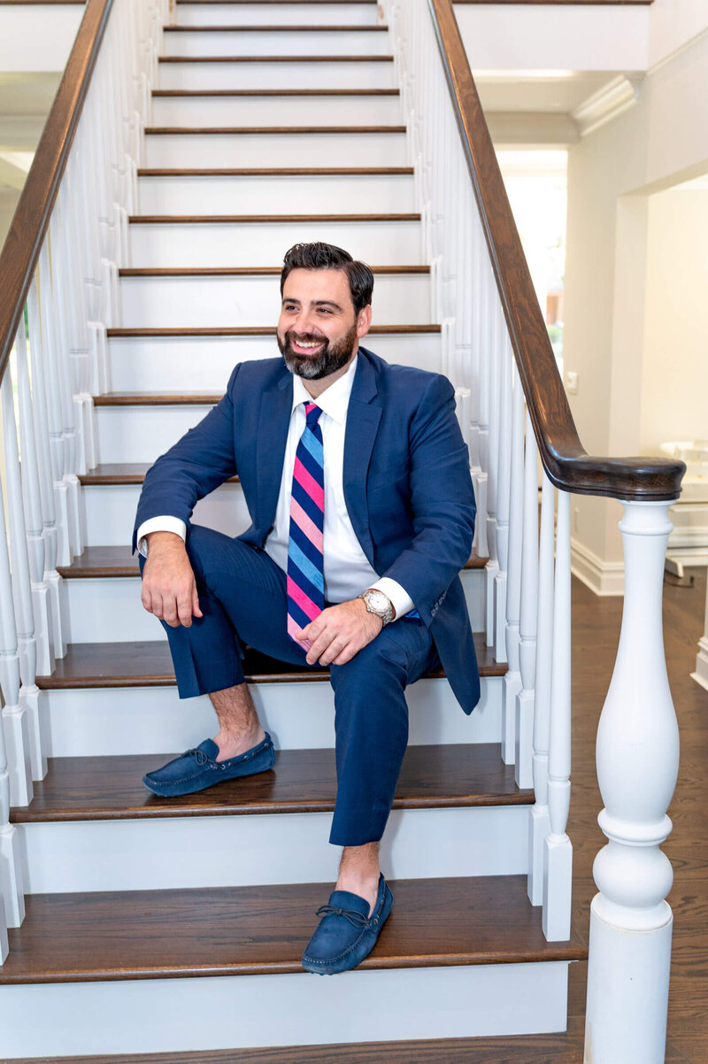 Real estate agent sitting on  impressive stairs in a newly renovated house in Greenwich, CT.