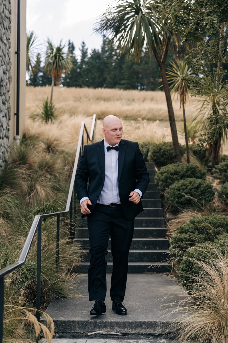 groom in tuxedo walks down steps at terrace downs resort on wedding day