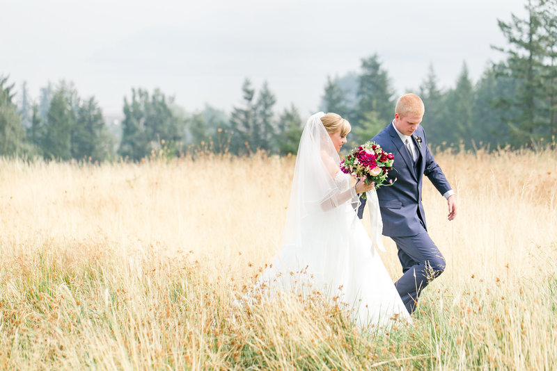 Bride and groom walking through a field