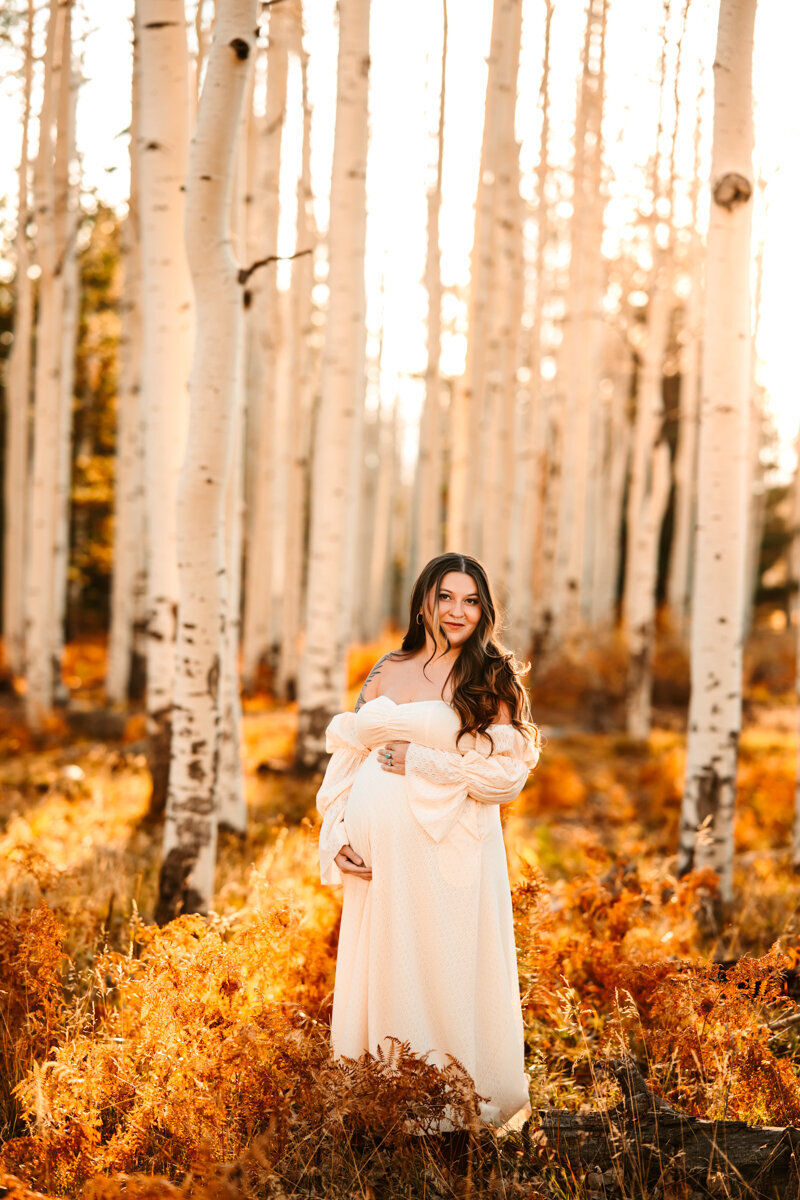 Aspen corner maternity session with woman holding her belly in a maxi dress from baltic born.
