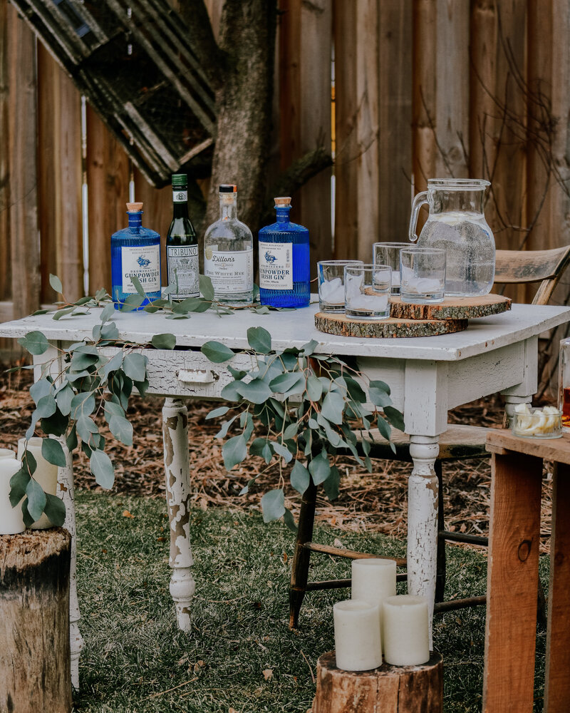 A rustic table set outdoors with Gin for a wedding or event.