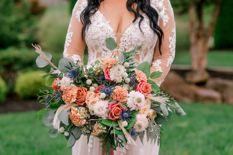 Close up of a bride holding a colorful bouquet of flowers.