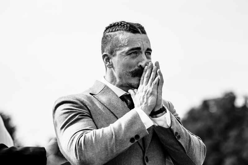 a crying groom holds his hands together in front of his face during the ceremony at the Stables in Whitehouse Ohio