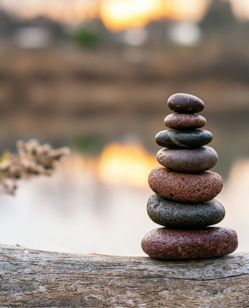 Chakra stones stack on a log by a lake. 