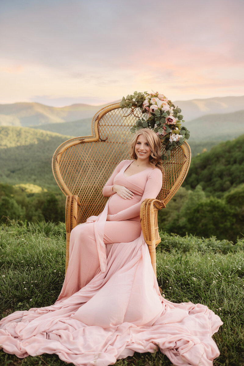 Expectant mother sits in a peacock chair during Maternity Photoshoot on the Blue Ridge Parkway in  Asheville, NC.