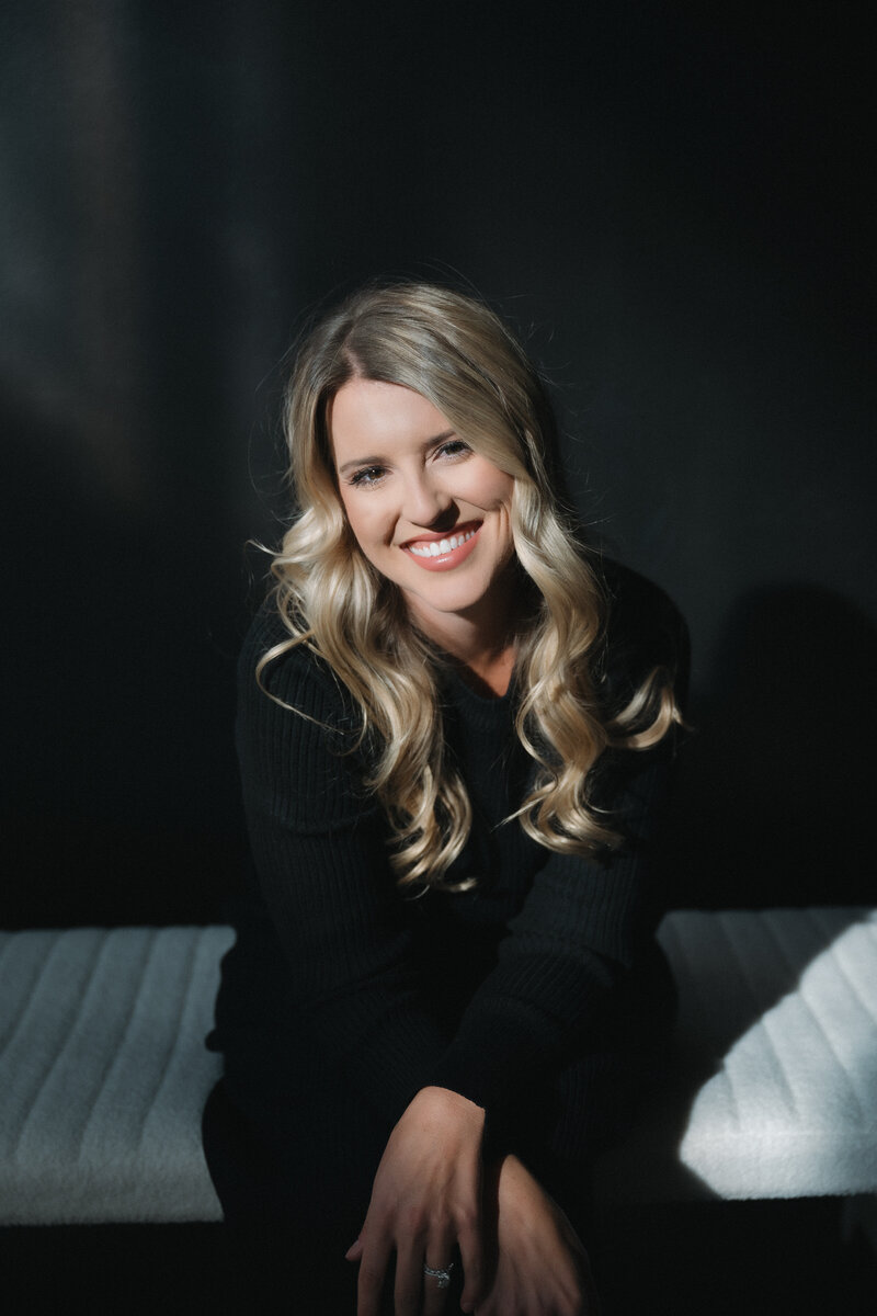 Professional headshot of Kansas wedding photographer Staci Brucks in natural setting with camera