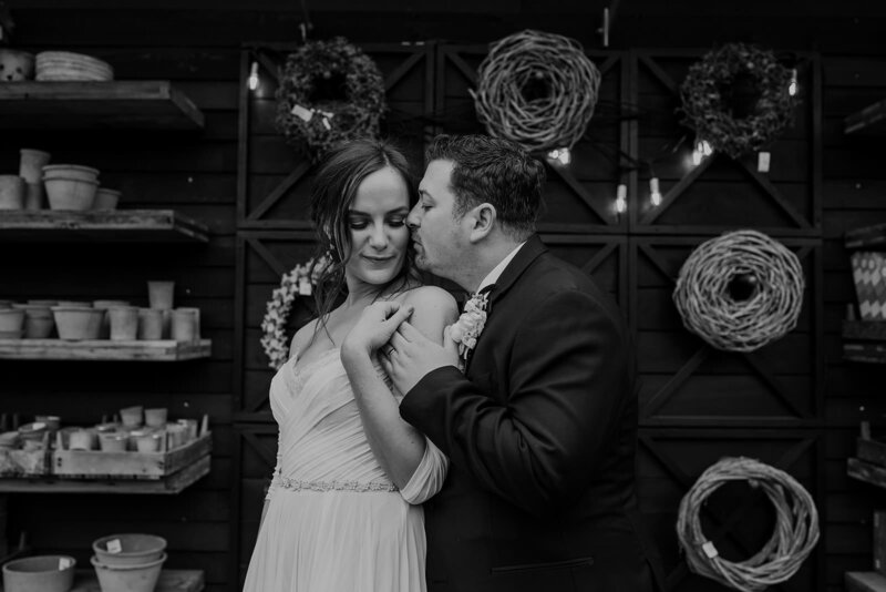 A person standing behind their partner kissing their cheek