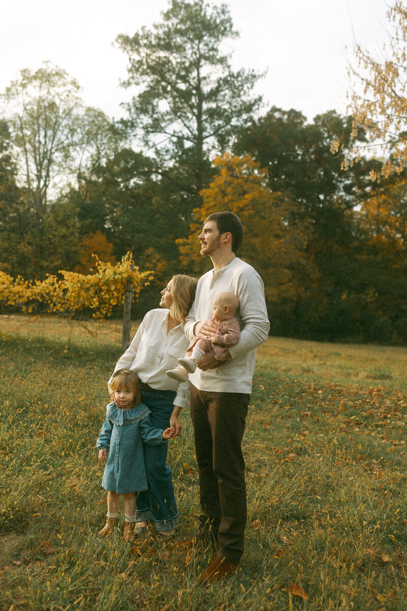 A family of four admire the sunset at Hyde Farm Park during a fall golden hour. 