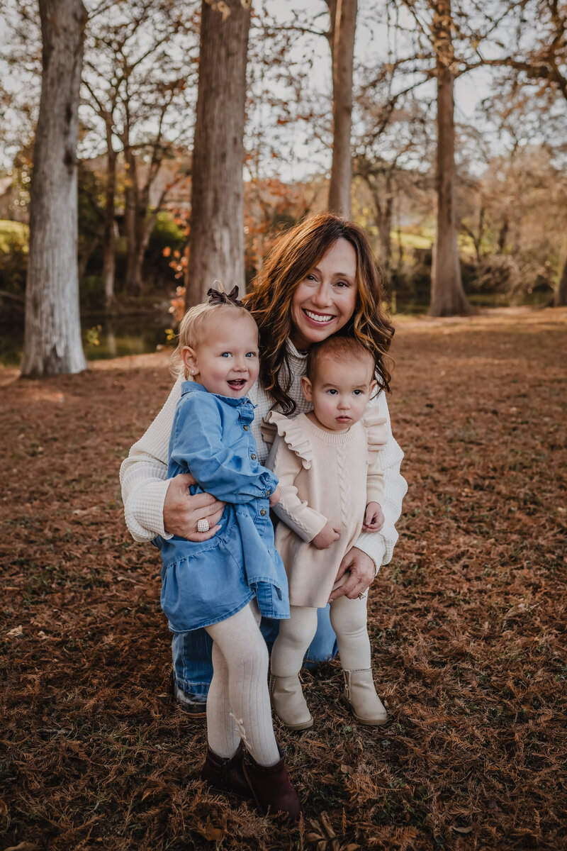 Grandmother with two granddaughters smiling together in park during lifestyle session in New Braunfels, Texas.