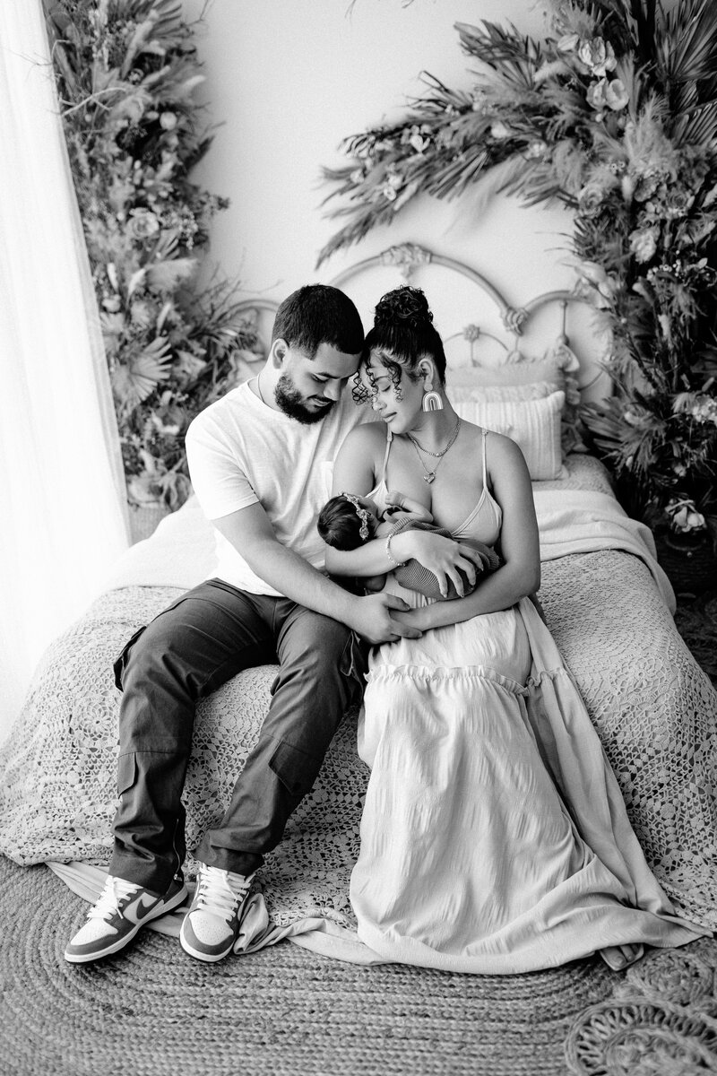 Newborn photography family photo woman with husband and baby on bed with boho background in Tampa Bay, Florida Nadine B Photography