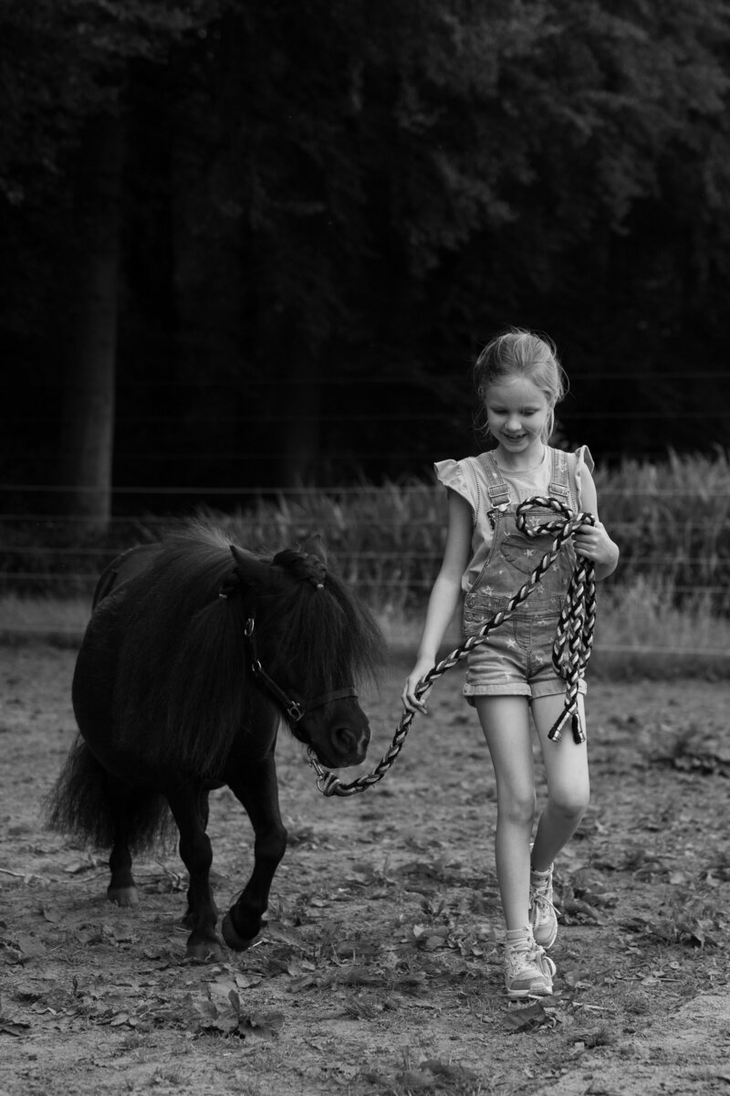 Meisje dat vol trots haar pony begeleidt tijdens coaching sessie.