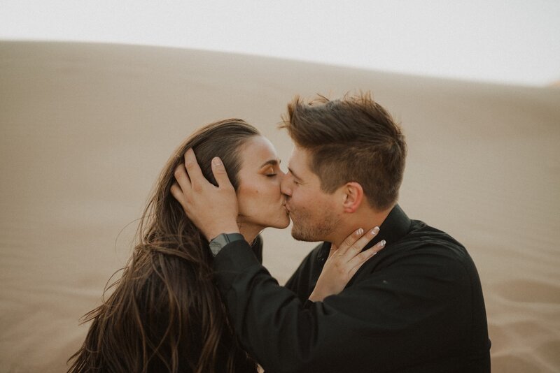 couple kissing in sand dunes