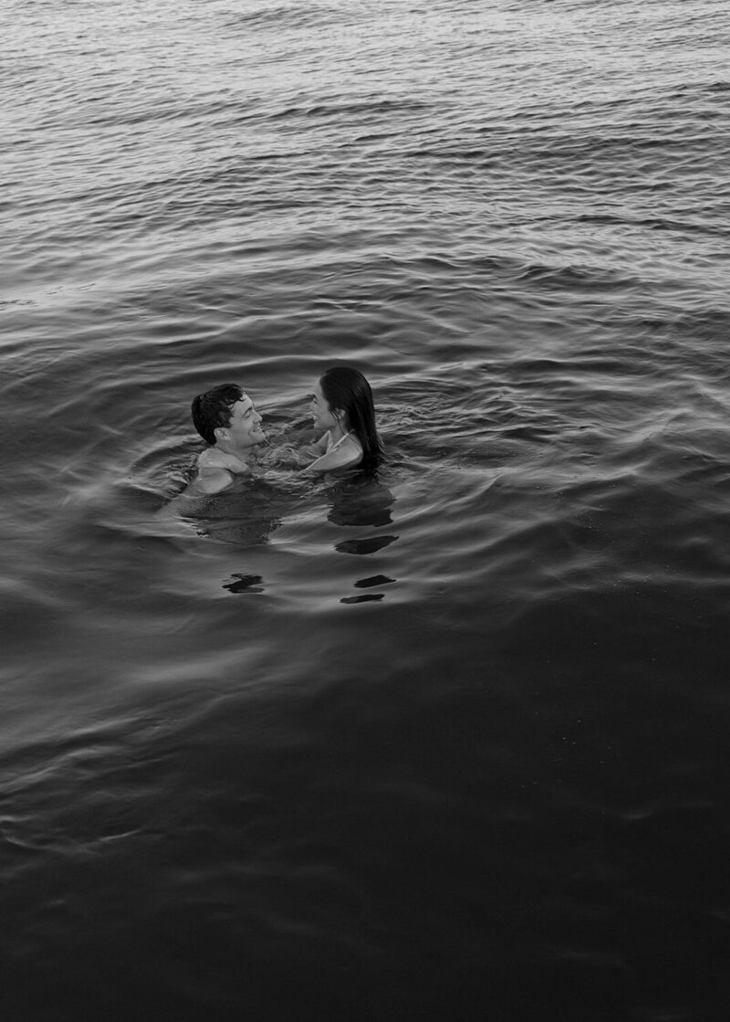 A black-and-white photo of two people swimming in open water