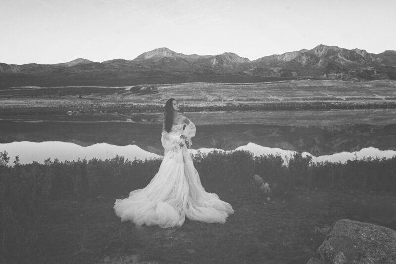 A beautiful woman wearing a couture bridal dress photographed in wild fields with snow capped mountains in the background.