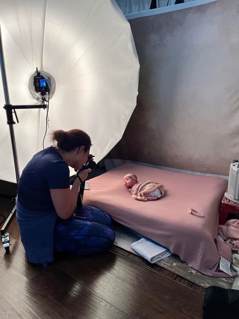 Houma newborn photographer Jamie Heyl holding her camera in a cozy studio setting