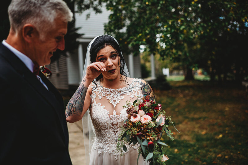 Bride and a sleeveless lace wedding dress wiping away at here as she stands with her father before her wedding ceremony at her Baltimore wedding venue captured by Baltimore wedding photographer