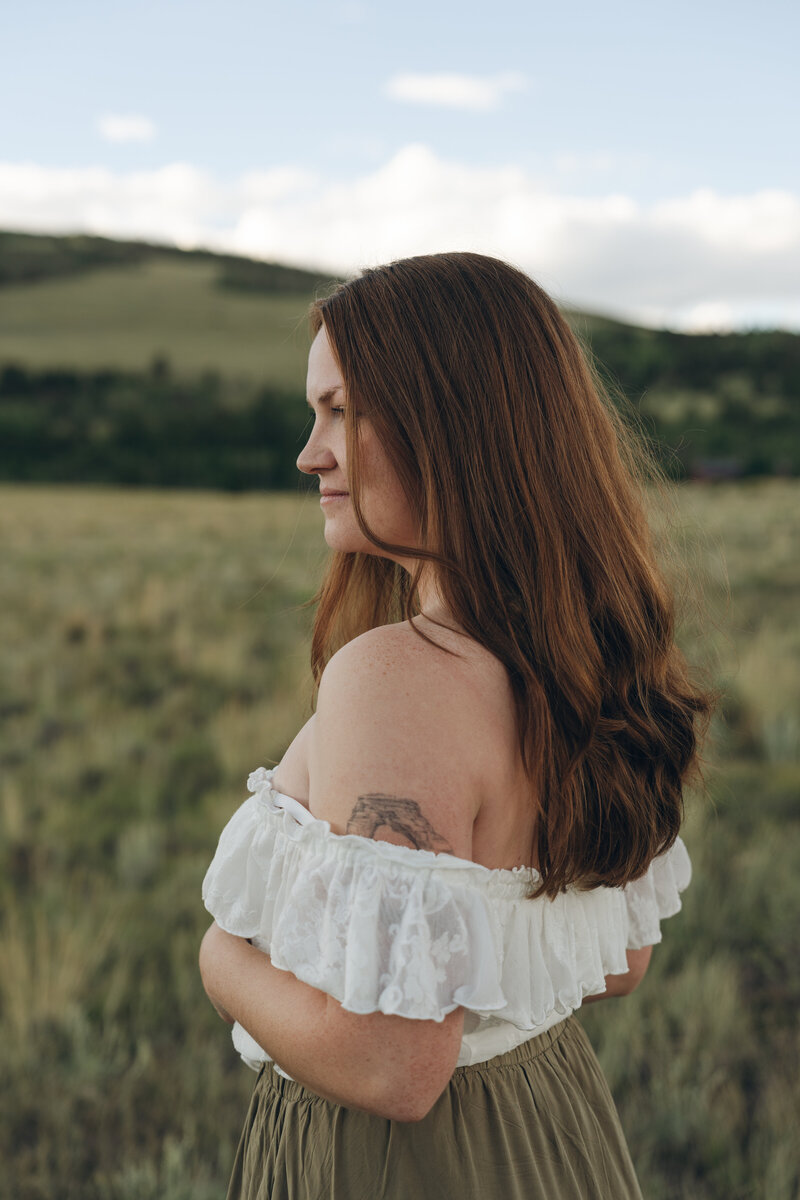 red haired woman looking into the distance in a Colorado field 