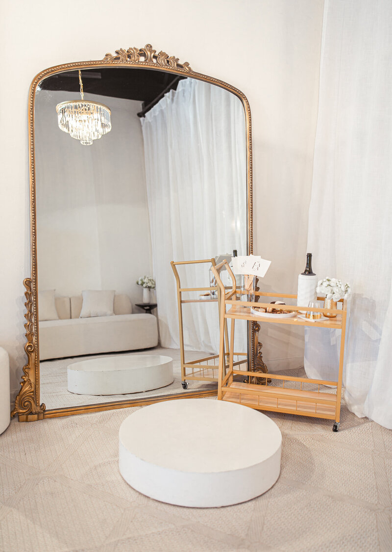 Bridal boutique semi private seating area with chandelier, and stage with a mirror for the bride to preview her wedding dress.