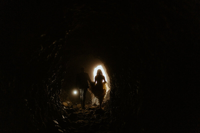 couple walking toward light in a cave