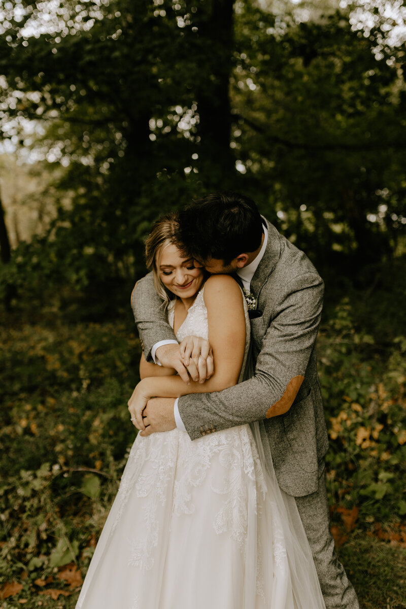 Groom hugging his bride from behind while she laughs