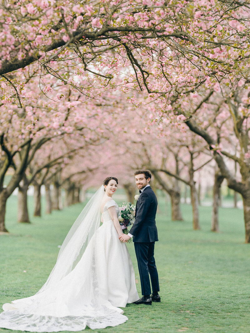 bride and groom surrounded by cherry blossom in Brooklyn Botanic Garden