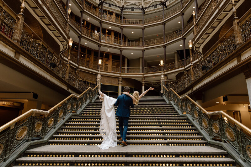 Bride and groom sitting on a bench in the Akron Art Museum with a gallery of paintings behind them. 