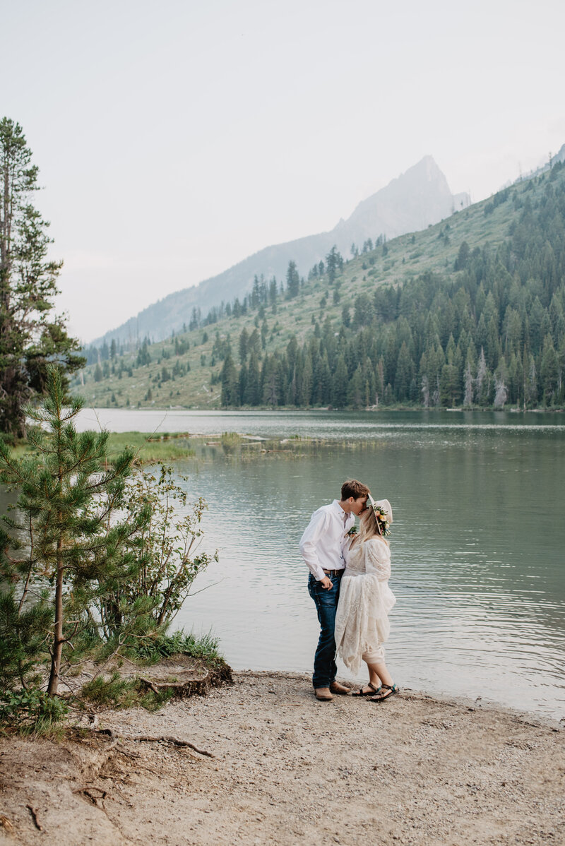 jackson hole photographers photographs bride adn groom kissing on the shore of Sting Lake for their wyoming elopement in the Grand Tetons