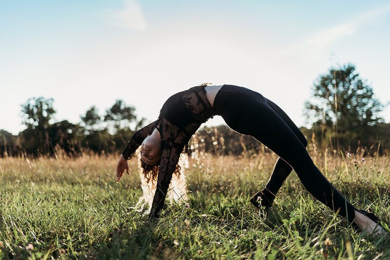 woman doing a wild thing yoga pose in a field during sunset