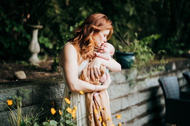 mom-holding-baby-boy-in-her-north-seattle-home-backyard