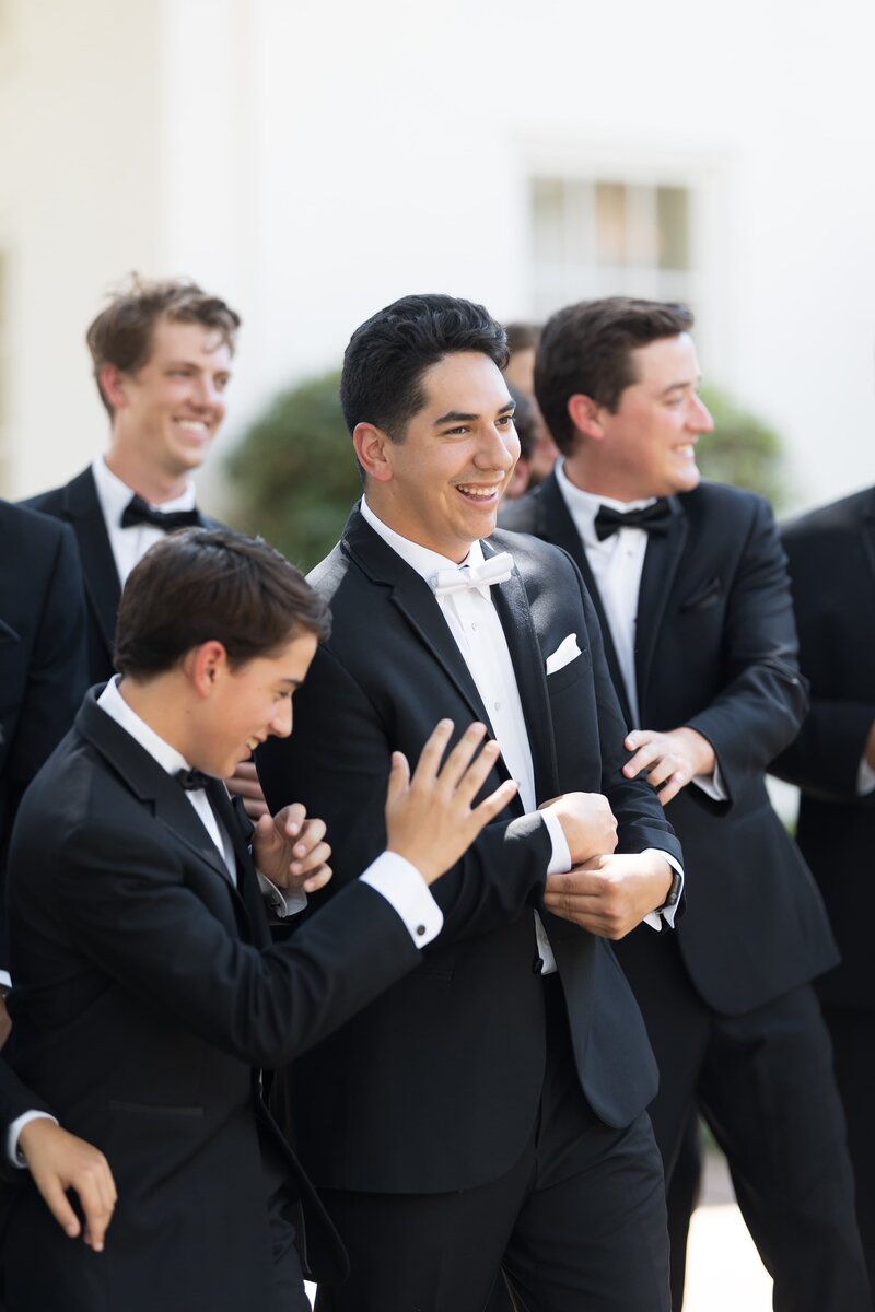 groom and his groomsmen smile and laugh in dark suits