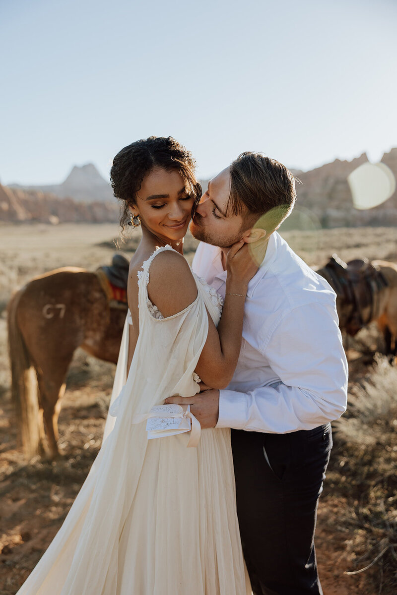 bride and groom embracing with horses in background
