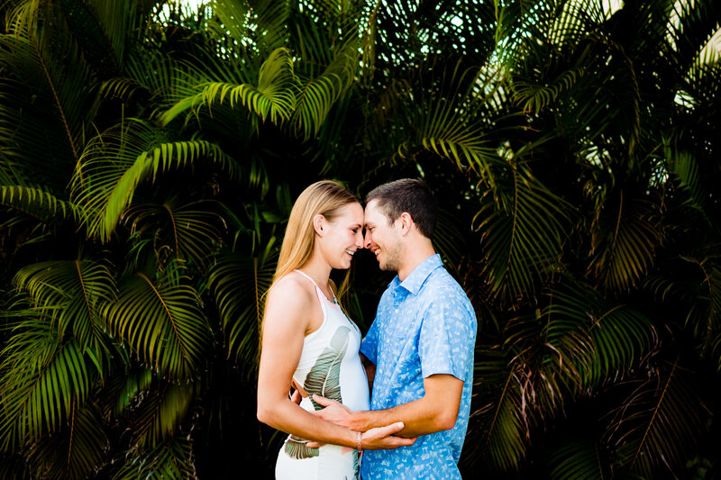 a engaged couple standing face to face in front of tropical plants in Punta Cana