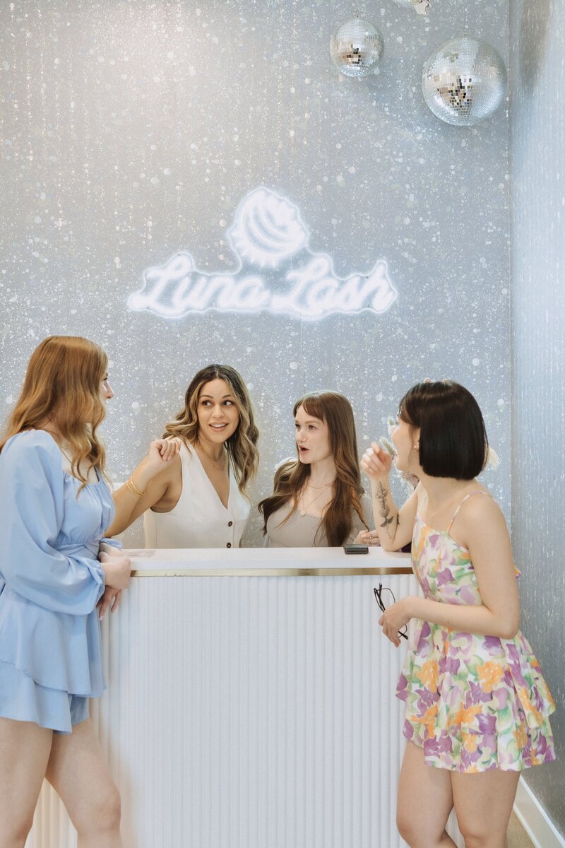 Luna Lash techs smiling and laughing at the front desk