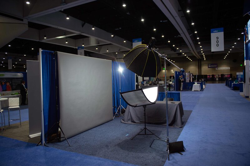 A headshot station studio setup is shown on the showroom floor at a large conference