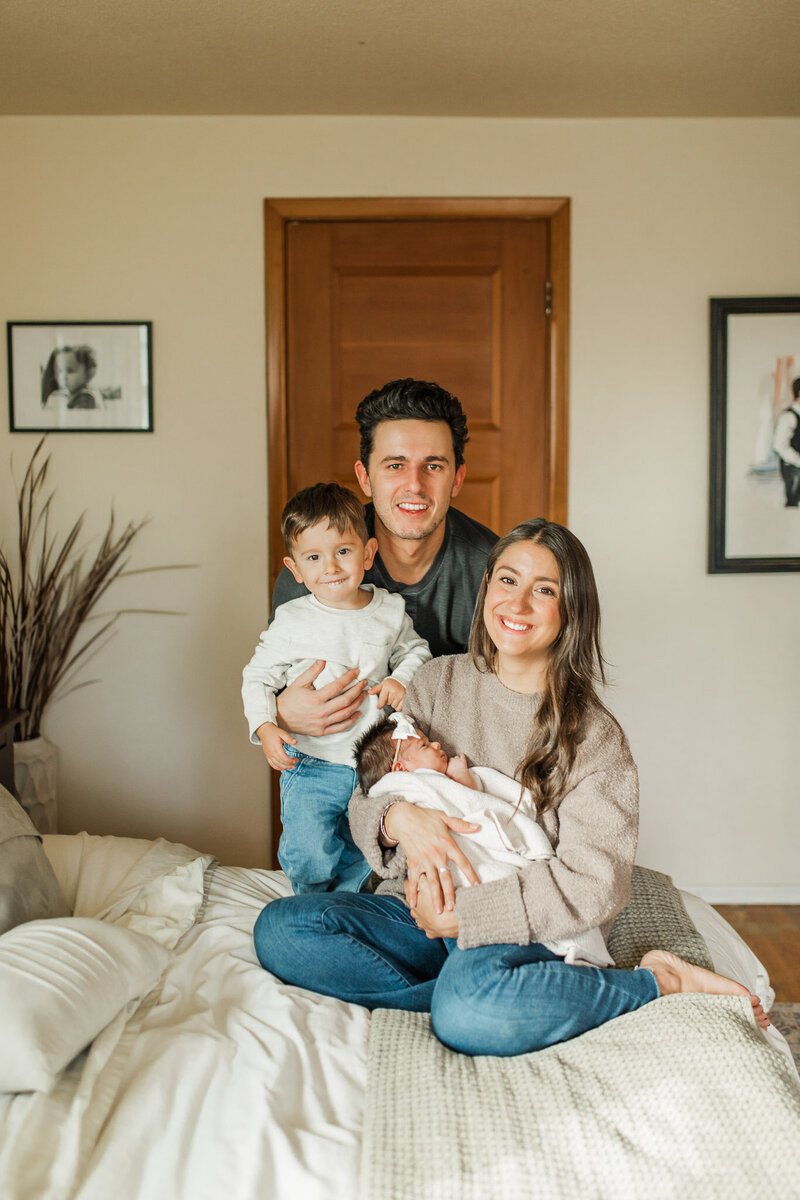 Family portrait on a bed, parents with two children